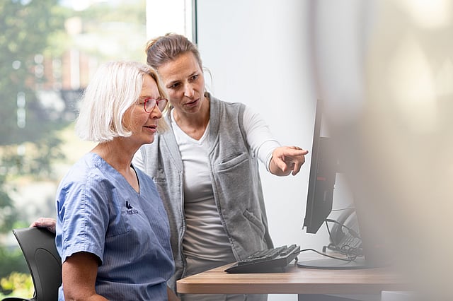 A person showing something on a computer to a person.
