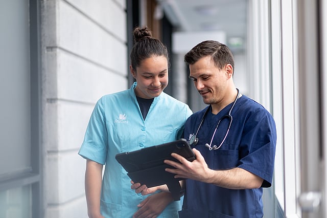 A person and person looking at a tablet.